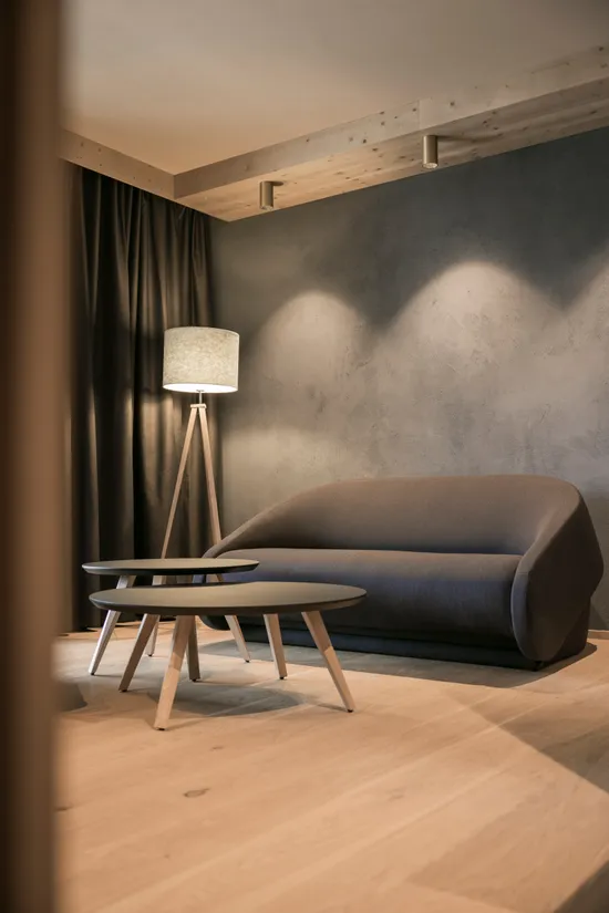 Modernes Wohnzimmer mit grauem Sofa, runden Couchtischen und Stehlampe auf Holzboden